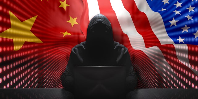Hacker anonimo davanti al suo computer con sfondo rosso muro Hacker anonimo che indossa una felpa con cappuccio nera con laptop davanti a sfondo icona con sicurezza informatica concetto di flussi binari.