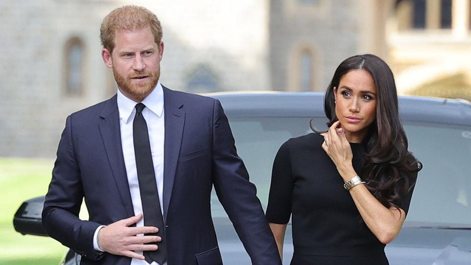 Il principe Harry indossa un abito blu scuro e una cravatta, tiene la mano di Meghan Markle e indossa un abito scuro dopo la morte della regina